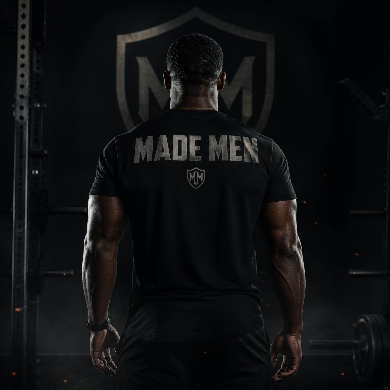 Muscular man from behind wearing a MADE MEN shirt in a dark gym